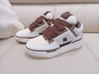 White low-top sneakers with brown laces and side logo patch, lace-up front