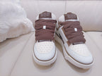 Pair of white low-top sneakers with brown knit tongues and laces