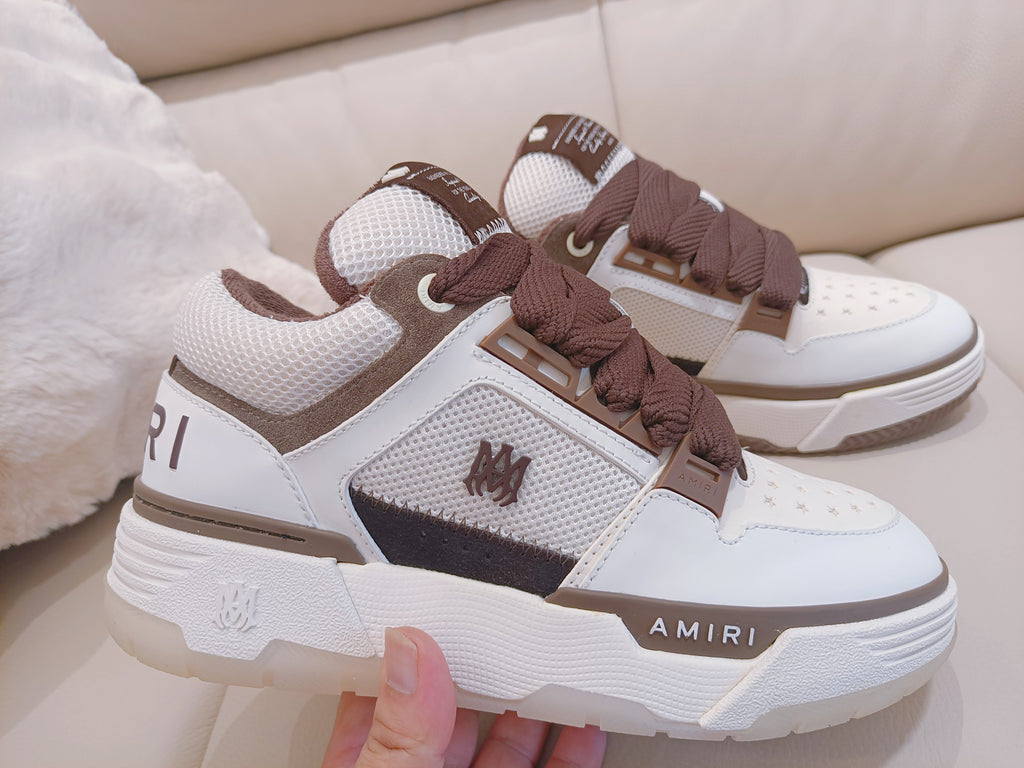 White low-top sneakers with brown laces, mesh panels, and AMIRI branding