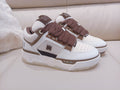 White low-top sneakers with brown laces and dark side stripe, logo accents