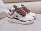 White low-top sneakers with brown laces and dark side stripe, logo accents