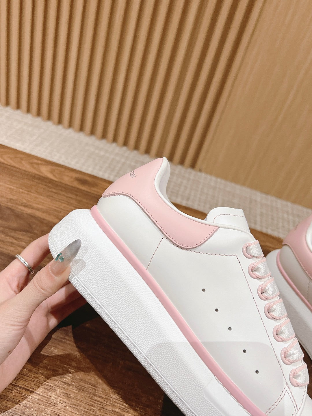 White leather low-top sneaker with pink heel panel and lace-up front
