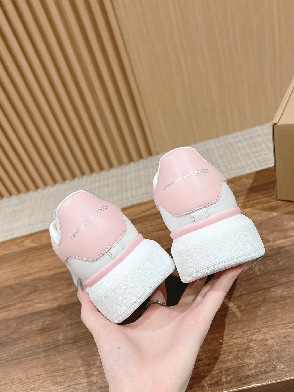 Pair of white sneakers with pink heel tabs and rounded low-profile outsoles