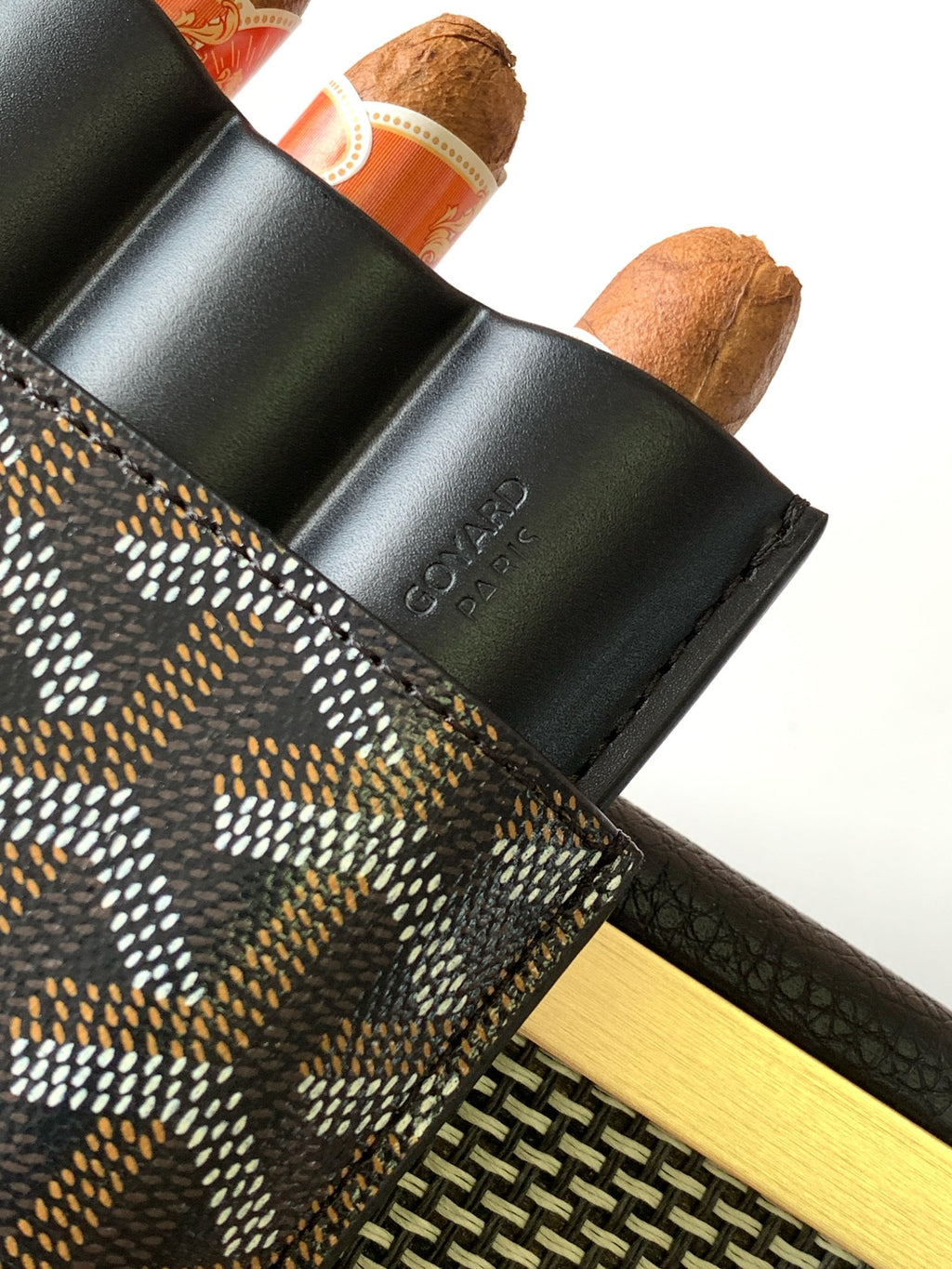 Goyard patterned bag with black leather flap and stamped text near edge