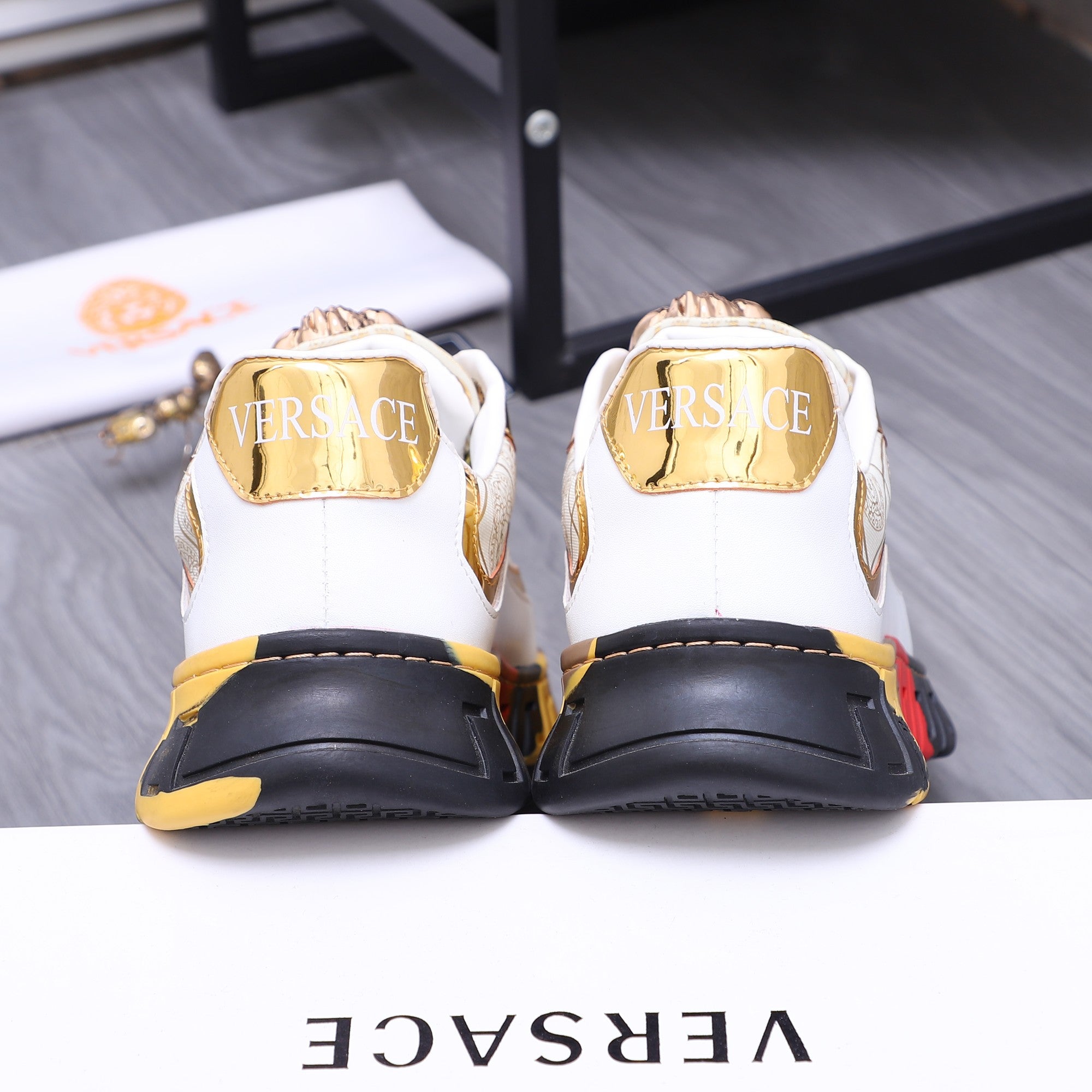Luxury sneakers back view: white heel counters with gold trim and chunky sole
