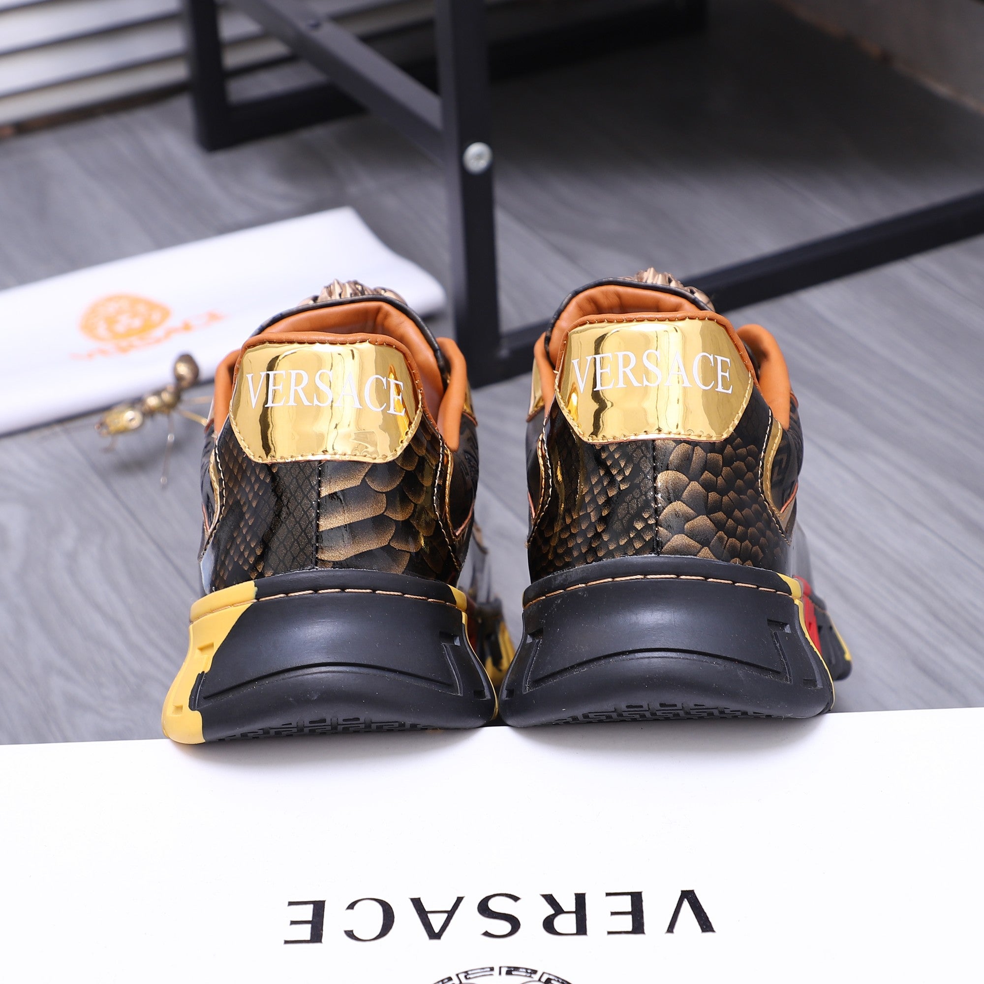 Luxury sneakers back view, black heel and navy patterned collar, gold accents, chunky sole