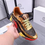 Luxury sneakers held in hand, gold Medusa emblem, navy upper, green laces, red/yellow sole