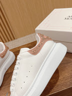 White leather lace-up sneaker with rose-gold glitter panel at collar, on a shelf