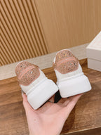 Two white low-top sneakers with rose-gold glitter heel patches and thick white soles