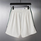White shorts with elastic waistband and green/black side stripe trim