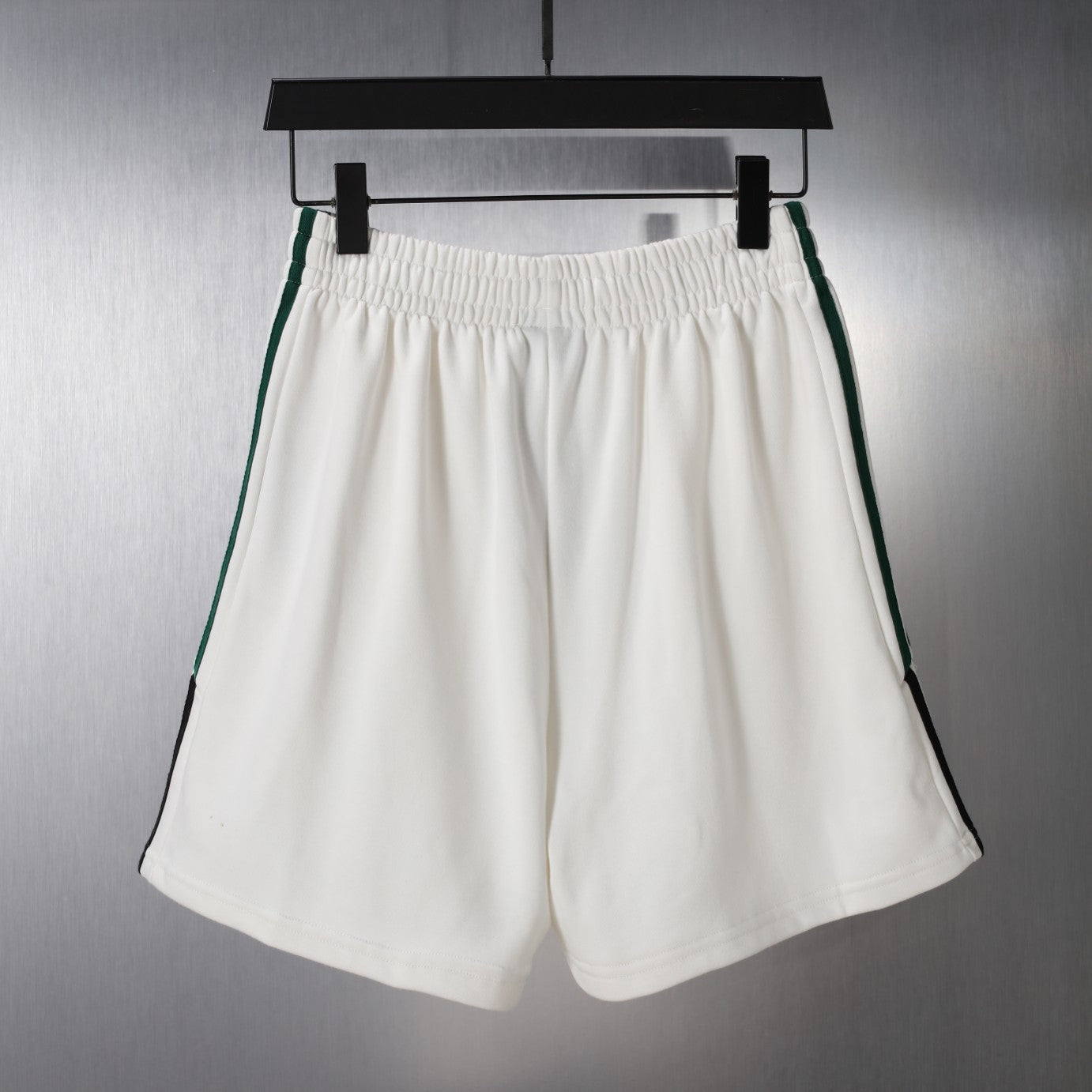 White shorts with elastic waistband and green/black side stripe trim