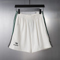 White shorts with elastic waistband and green/black side stripes