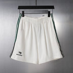 White shorts with elastic waistband and green/black side stripes