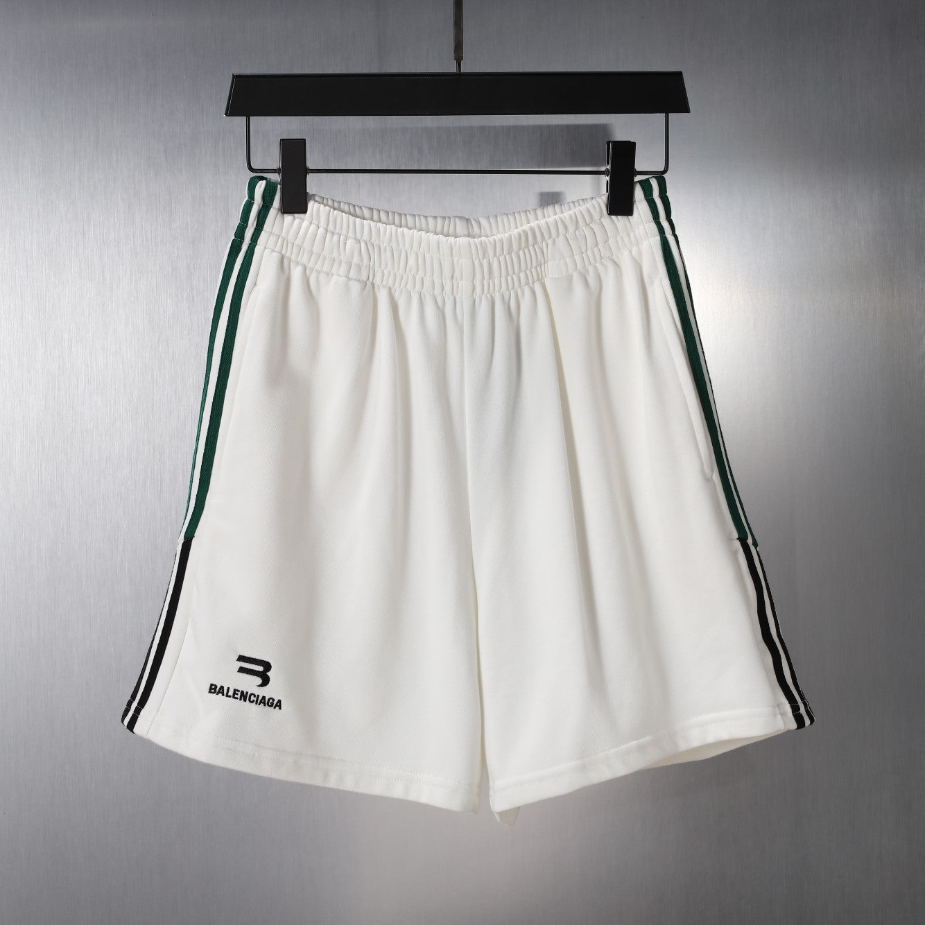 White shorts with elastic waistband and green/black side stripes
