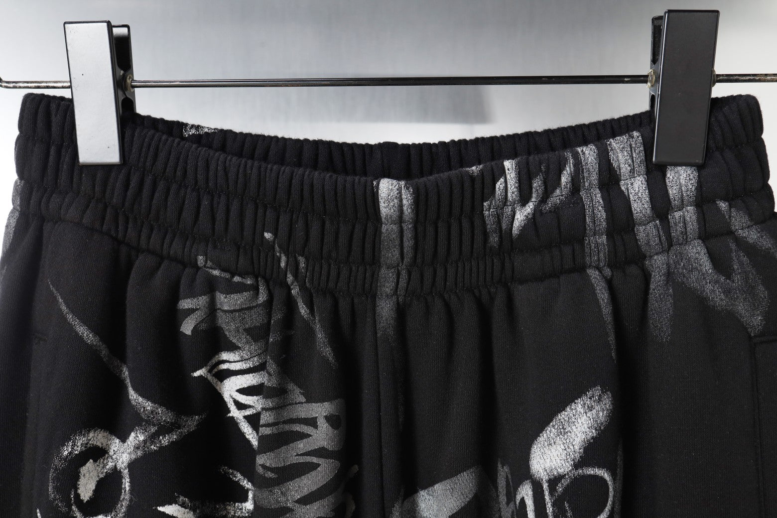 Black pants waistband with elastic gather and metallic clip detail
