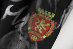 Black pants fabric with embroidered crest patch and red-green detail