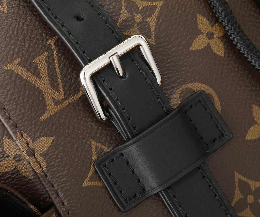 Louis Vuitton monogram backpack strap attachment with black leather tab and metal buckle.