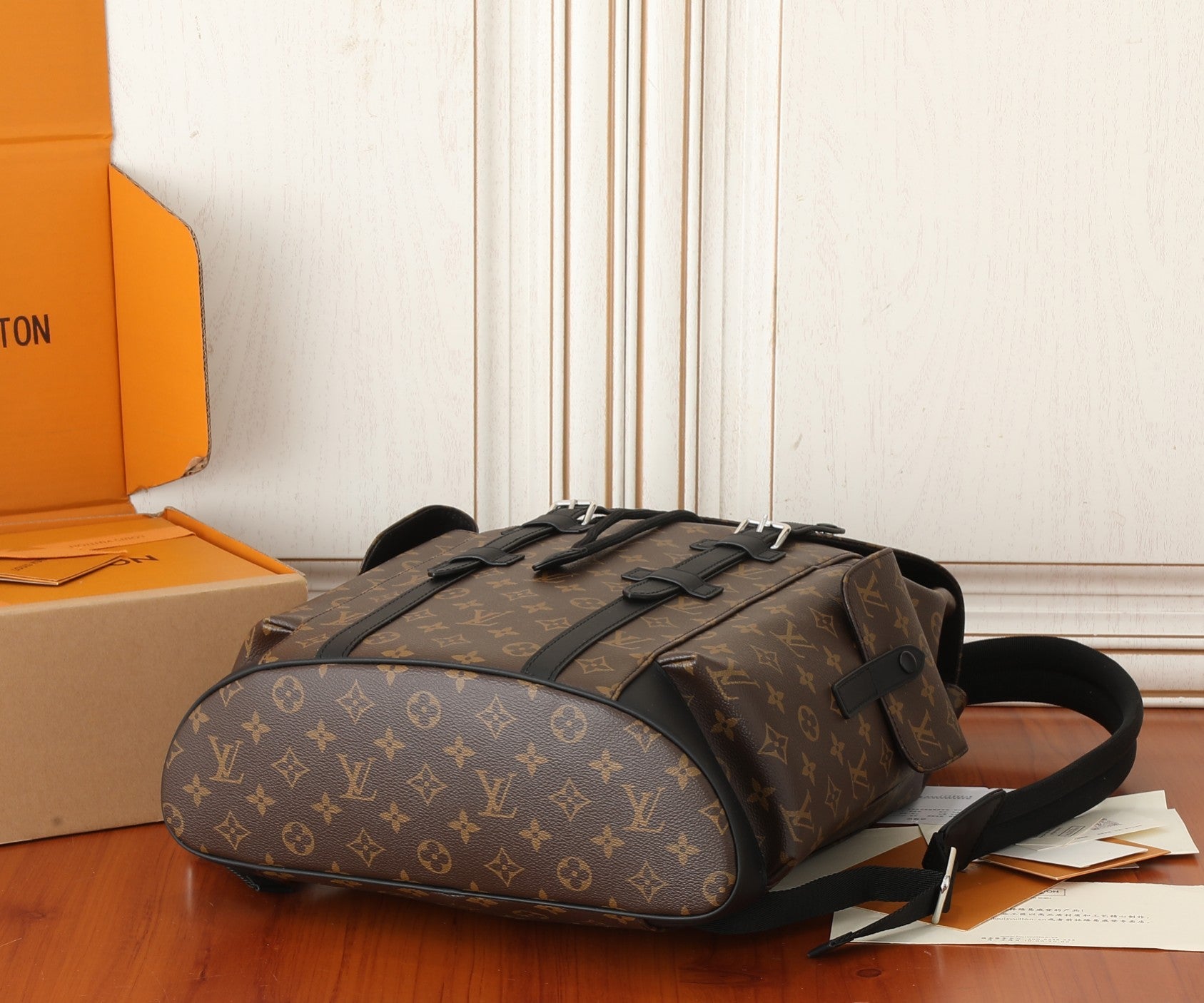 Monogram duffel-style backpack with top handle, front buckle tabs, and black trim