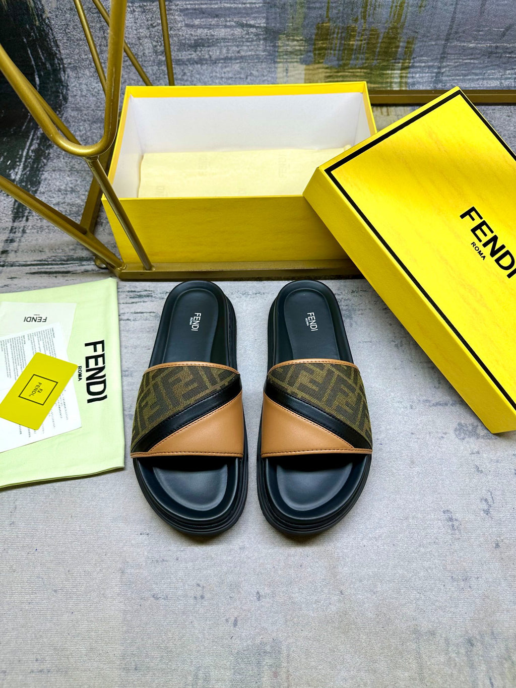 Black Fendi slide sandals with FF monogram straps and tan V-shaped leather trim
