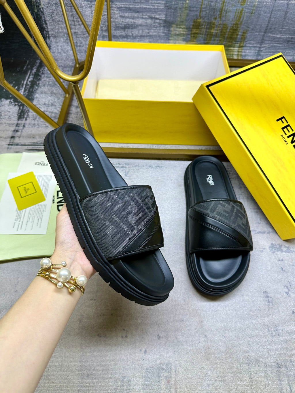 Black Fendi slide sandals with FF-pattern strap and wide band, slip-on style.