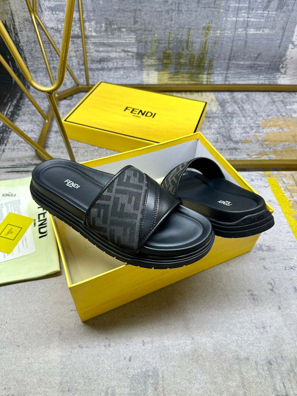 Black Fendi slide sandals with FF strap and logo footbed, angled pair.