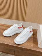White leather low-top sneakers with red collar accent, laces and perforated detailing