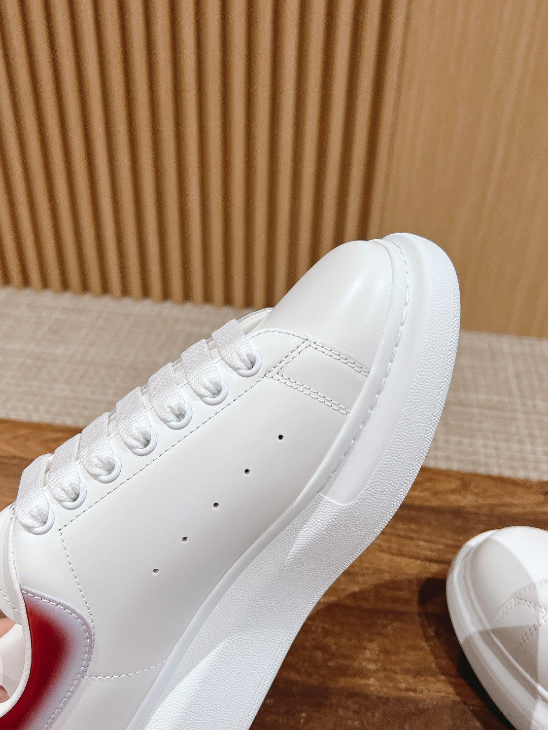 Close-up of white sneaker upper with perforated toe and lace eyelets.