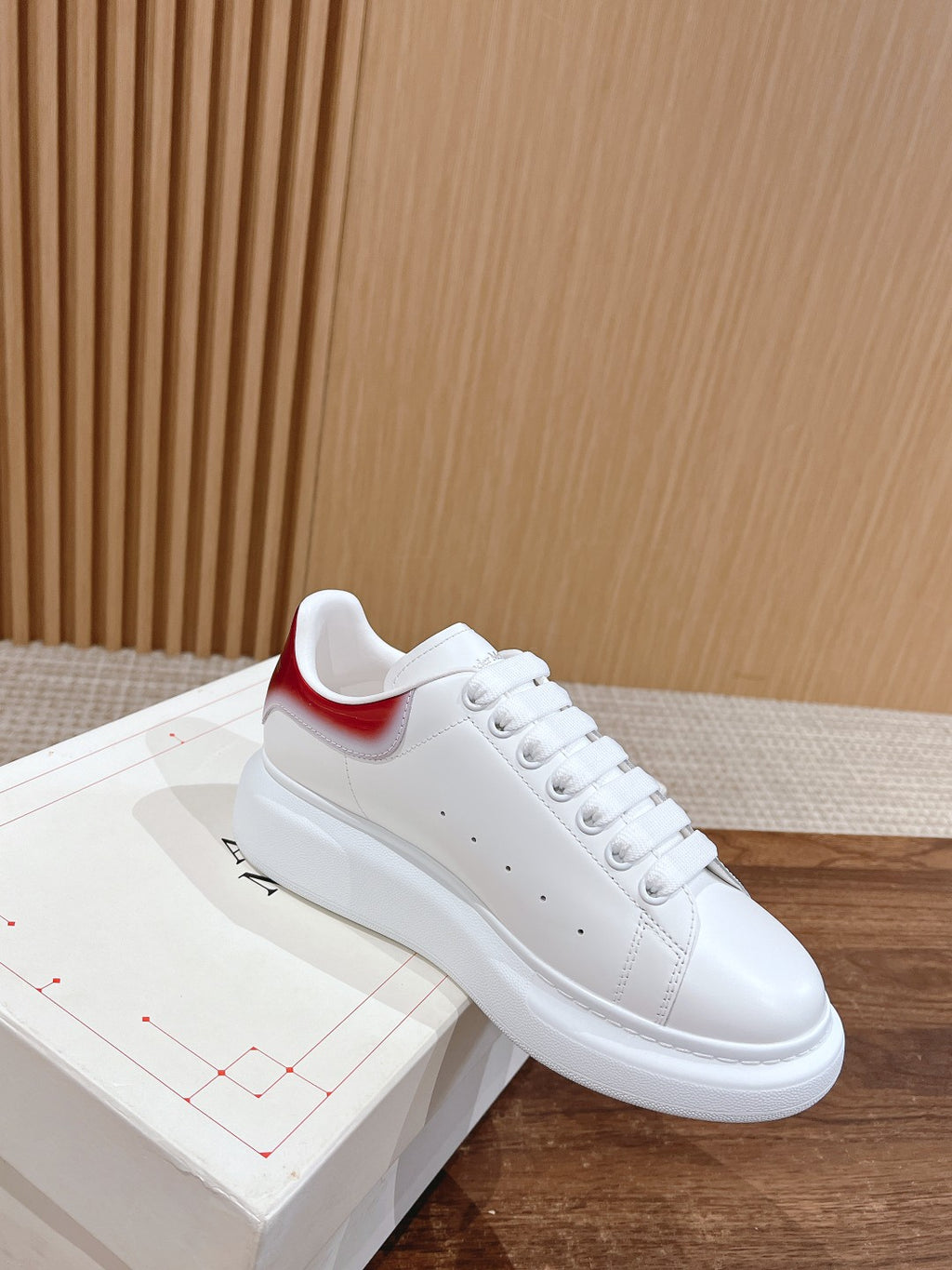 White leather sneakers with red Nike-style heel tab, lace-up front and smooth sole