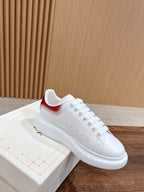 White leather sneakers with red Nike-style heel tab, lace-up front and smooth sole