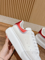 White leather sneakers with red collar accent and perforated panel detail, side view