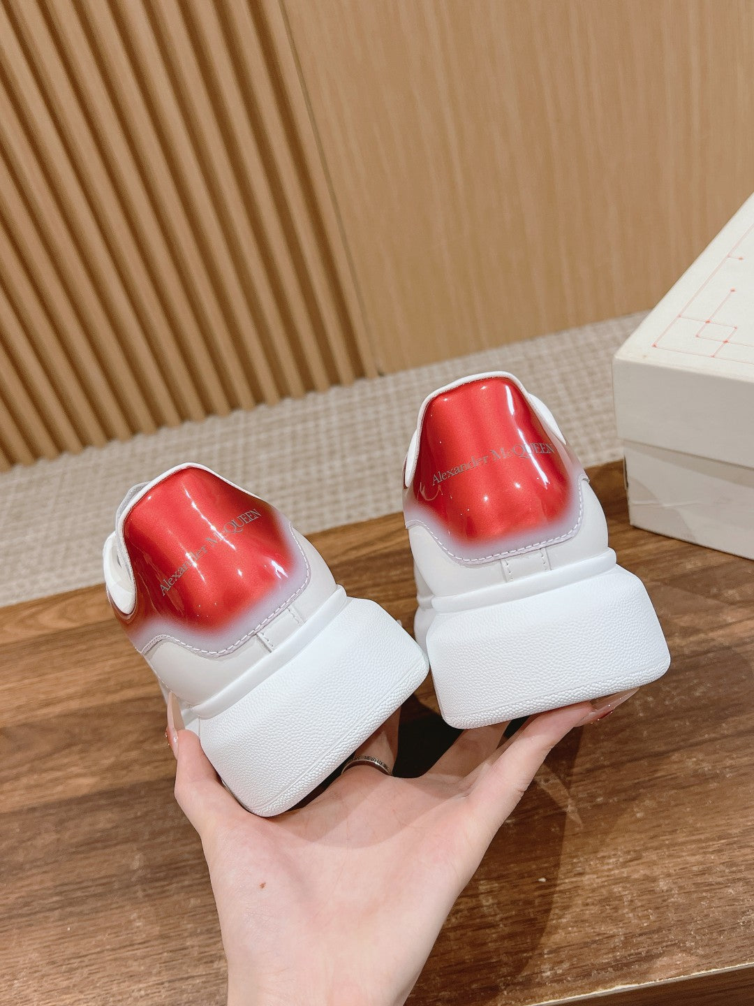 White sneakers showing red heel backs and textured rubber sole, held side by side