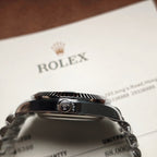 Rolex wristwatch crown and case close-up with dark caseback and metal bracelet