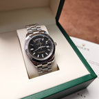 Rolex wristwatch in gift box with green stripe, black dial and silver-tone bracelet