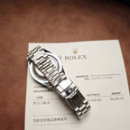 Rolex wristwatch with silver-tone metal bracelet resting on receipt paper