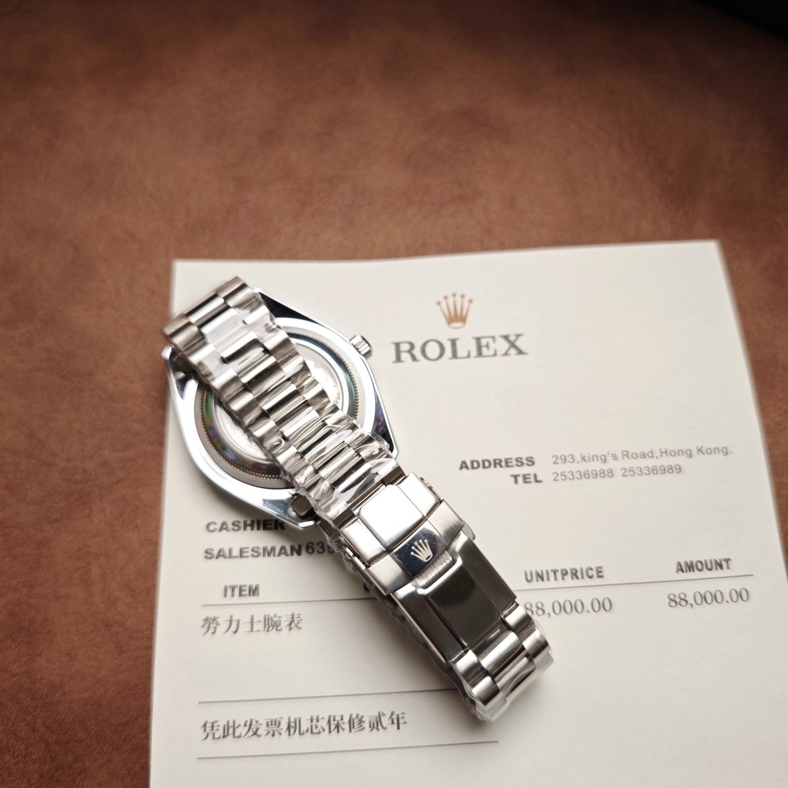 Stainless steel Rolex wristwatch with bracelet and clasp, shown on paper