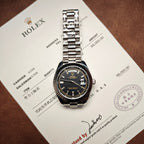 Rolex wristwatch with silver-tone bracelet on certificate card, black dial and date display