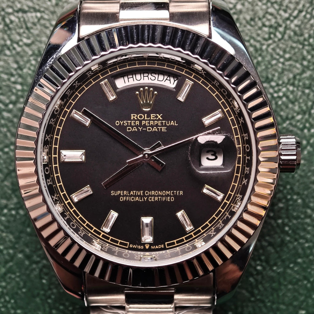 Rolex Day-Date wristwatch close-up, black dial, fluted bezel, day-date markers at 12 and 3