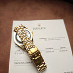 Gold-tone Rolex watch on paper, black dial, metal bracelet