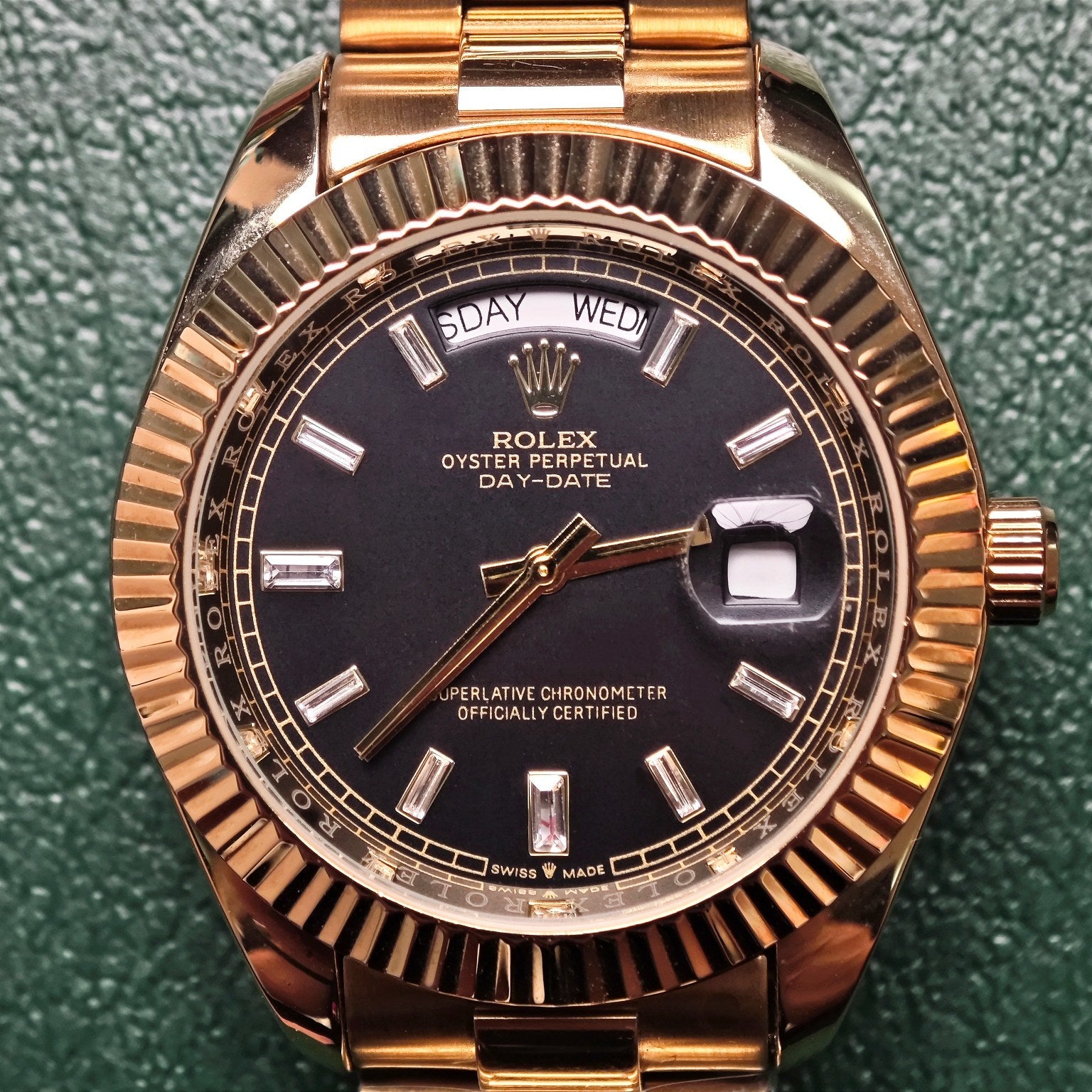 Gold-tone Rolex watch dial with 'DAY-DATE', black face, metal bracelet