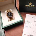 Gold-tone Rolex watch in green-and-white box, black dial, metal bracelet