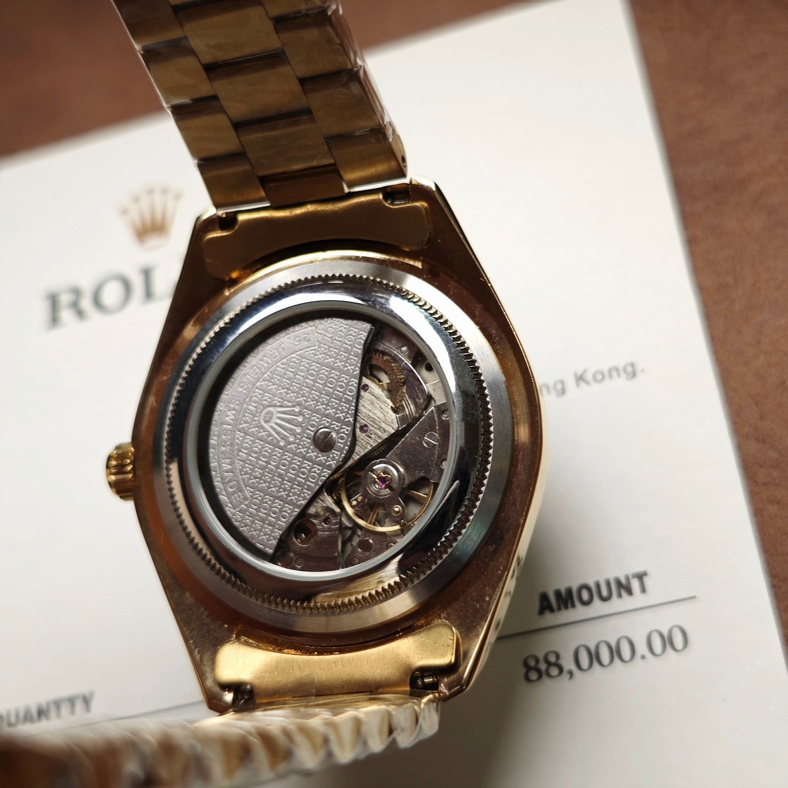 Open gold-tone Rolex watch caseback with visible movement and textured dial