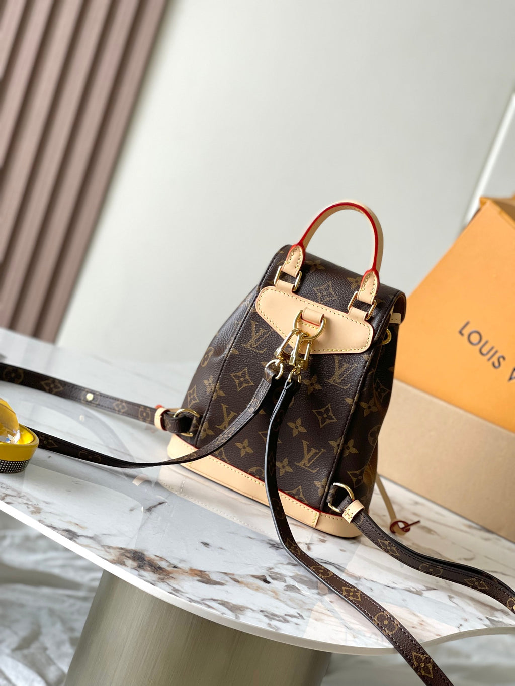 Louis Vuitton monogram mini backpack with tan flap, red strap trim, and crossbody strap
