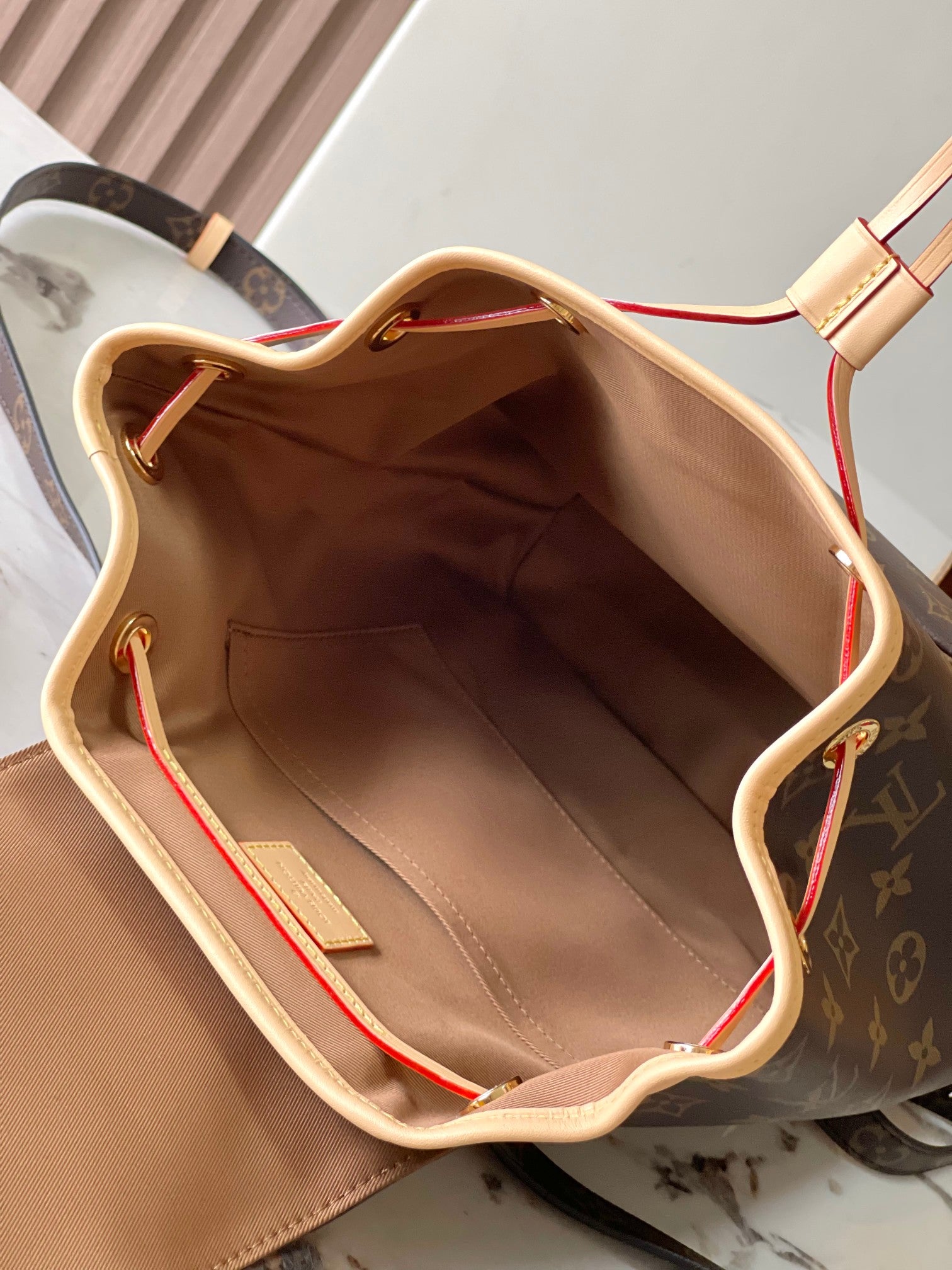 Monogram canvas bag interior with tan lining and red-and-blue trim accents