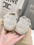 Luxury shoes by Golden Goose: light beige sneakers back view, heel panels held in hand