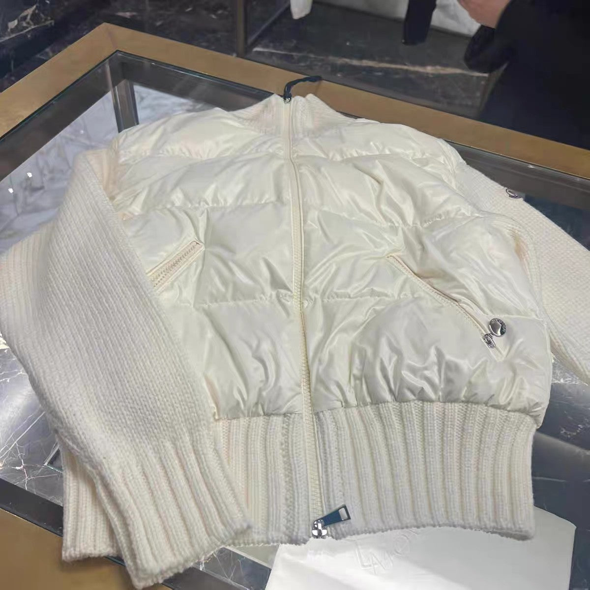 Moncler white puffer jacket laid flat, zip front and knit ribbed hem.
