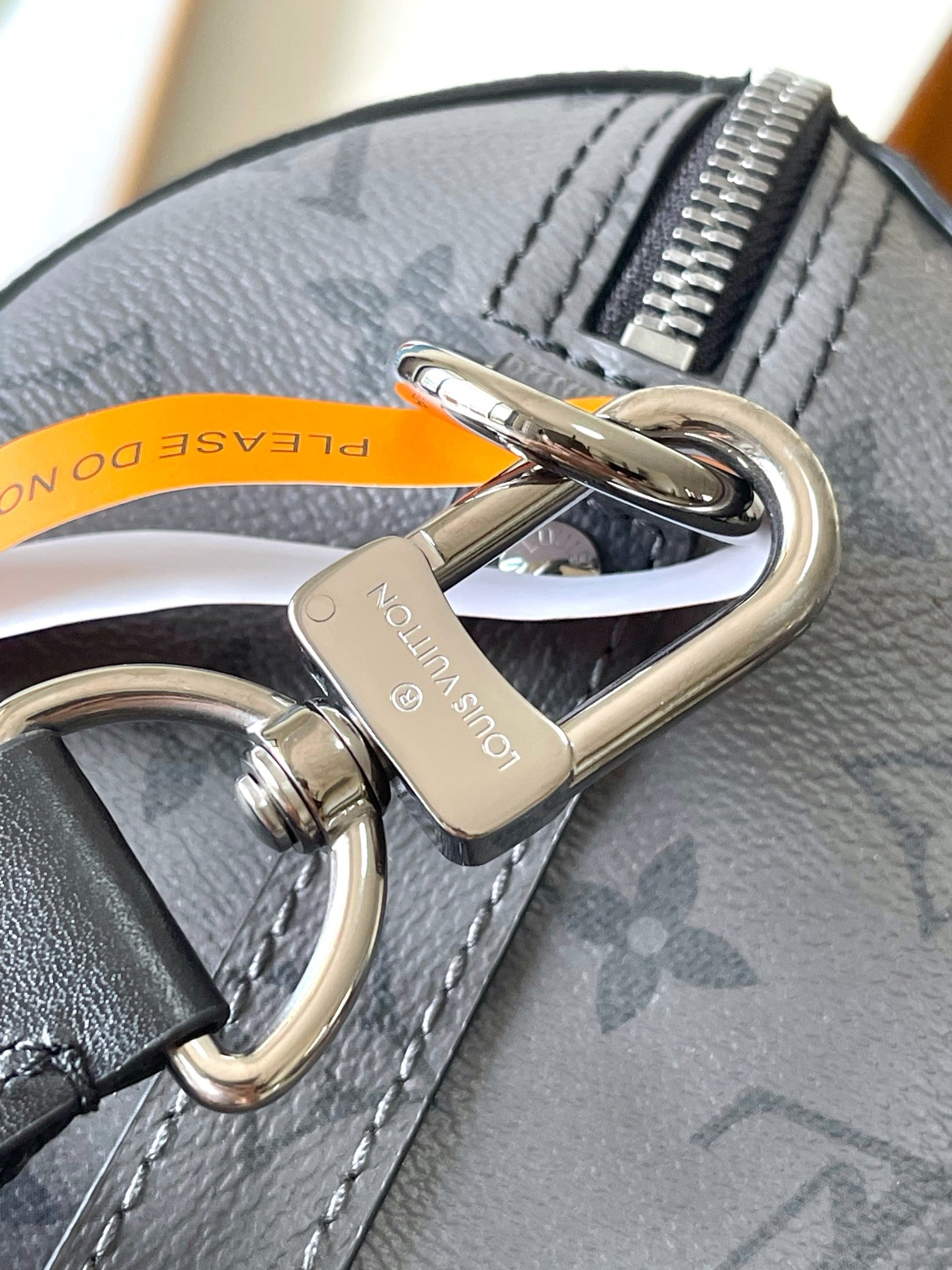 Louis Vuitton strap rings with silver hardware on dark monogram bag, close-up