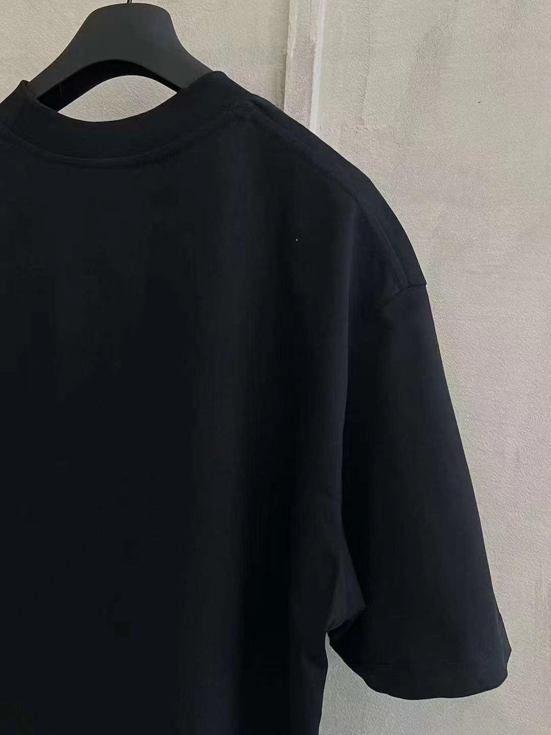 Black T-shirt with crew neck and short sleeves, side view