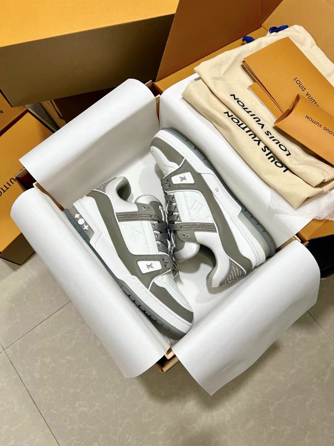 Louis Vuitton trainer sneakers, open box view showing side panels and gray sole