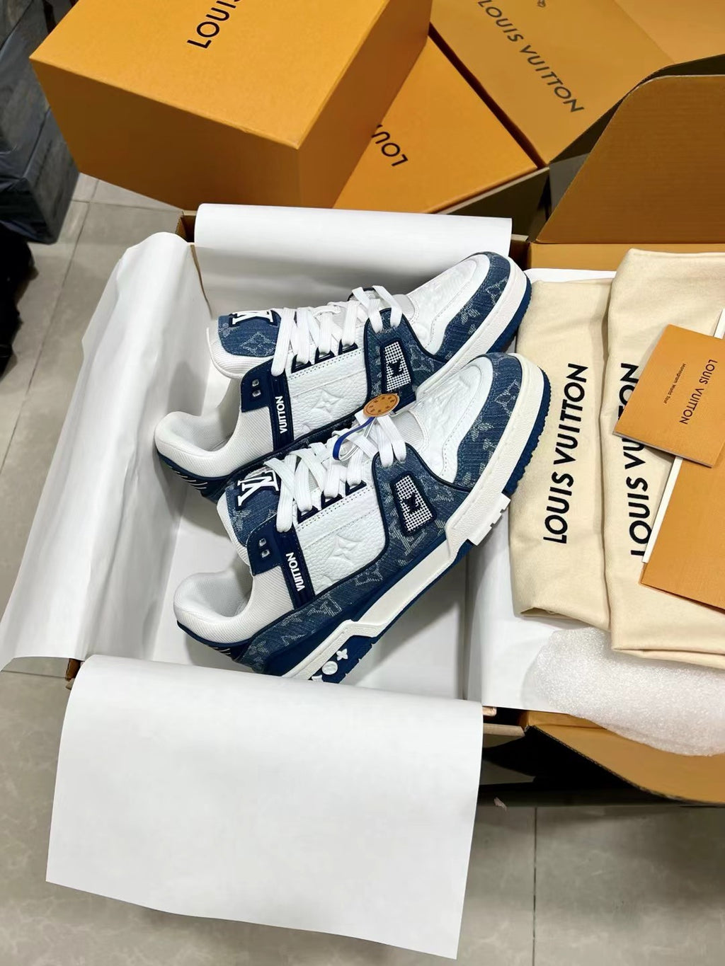 Louis Vuitton trainer shoes, close-up in box with blue-and-white patch details
