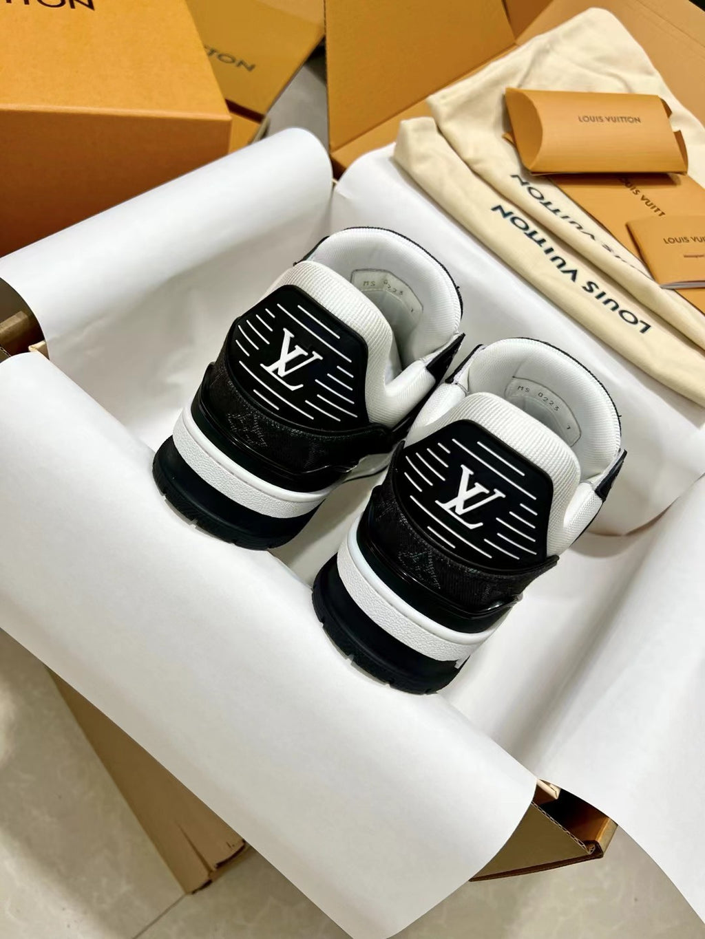 Low-top trainer sneakers close-up, black and white with LV monogram on tongue